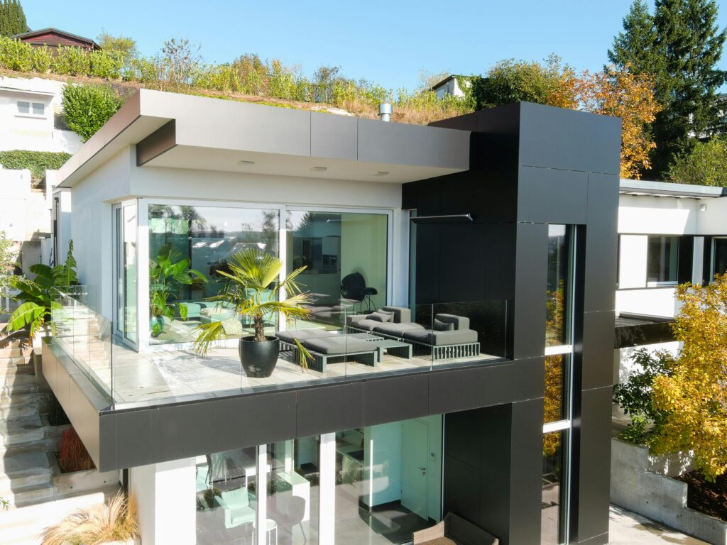 Contemporary house featuring glass balcony, lush plants, and stylish design.