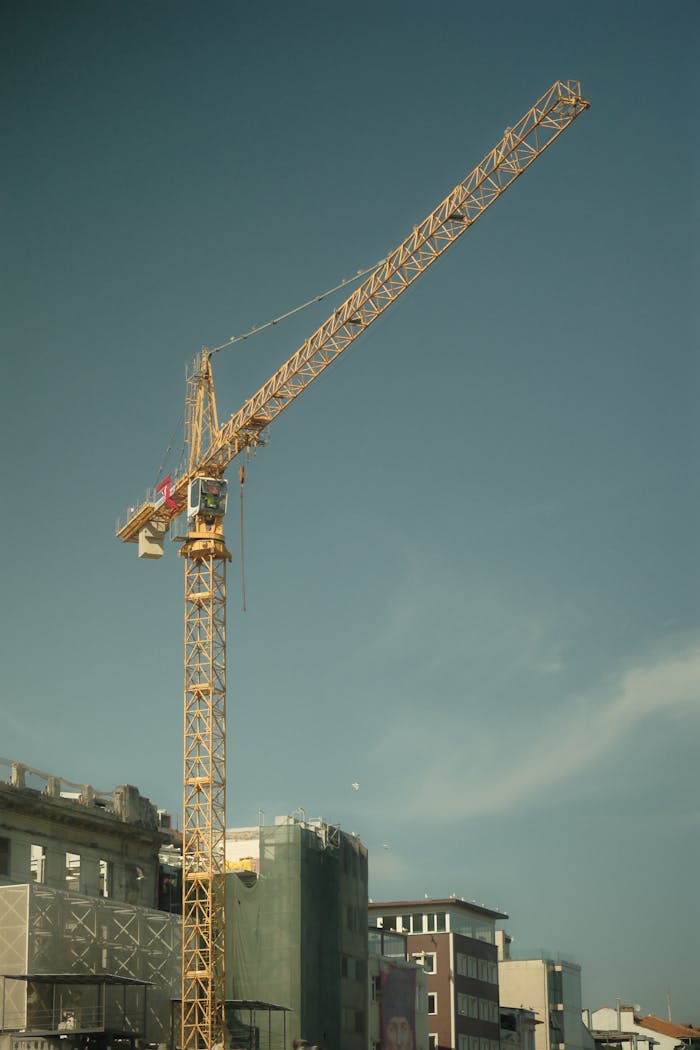 Tower crane at a construction site with a clear sky backdrop, highlighting urban development.